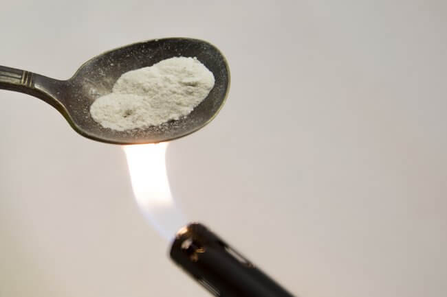 Crushed fentanyl in spoon being burned by a lighter.